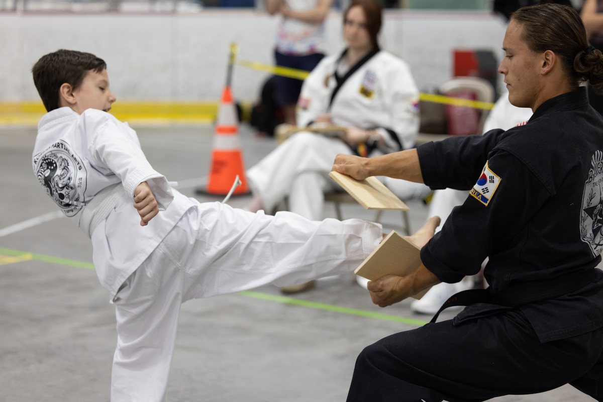 Young competitor breaking a board with a side kick