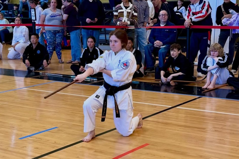 Competitor kneeling with a bo staff during a weapons form